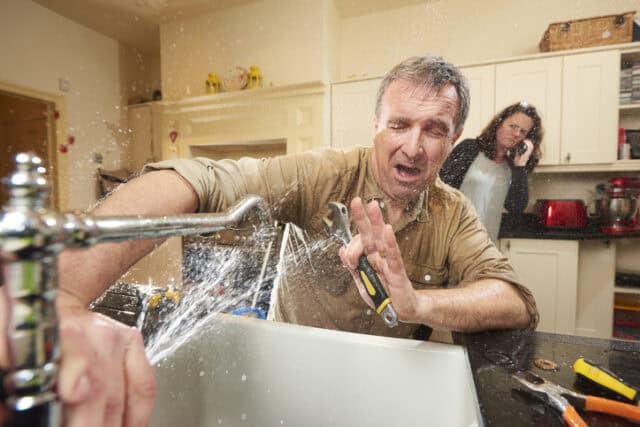 man being sprayed wiht water from plumbing mishap