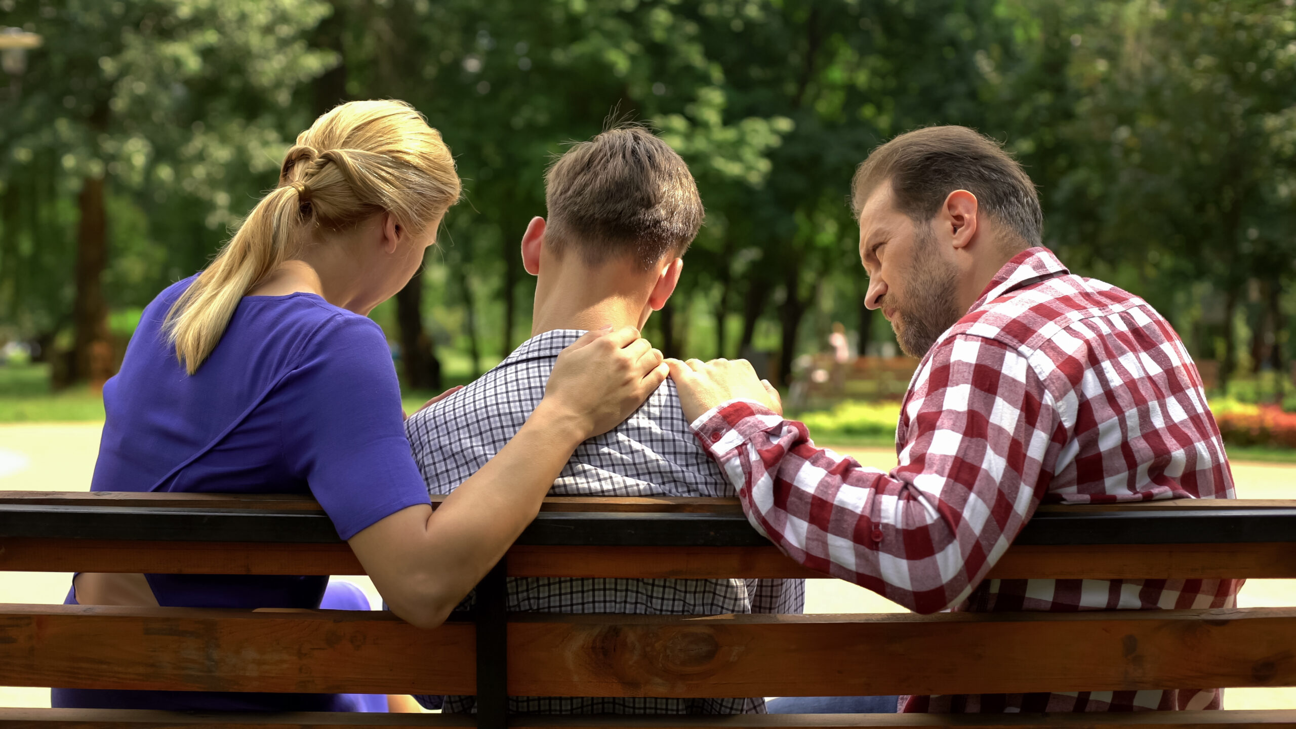 Parents speaking outside with their teenage son.