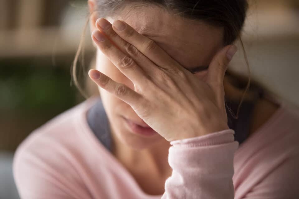 Tired woman with her hand over her eyes.