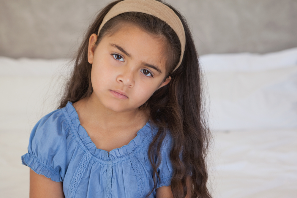 Serious little girl sitting alone.