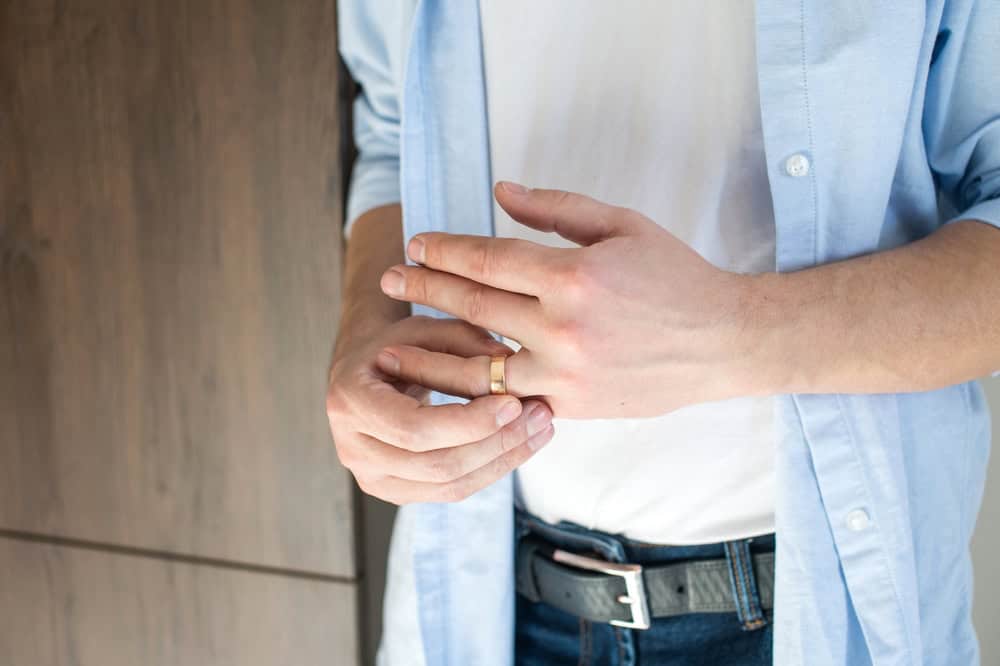 A man removes his gold wedding band.