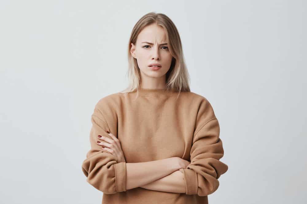 A woman frowning with crossed arms.