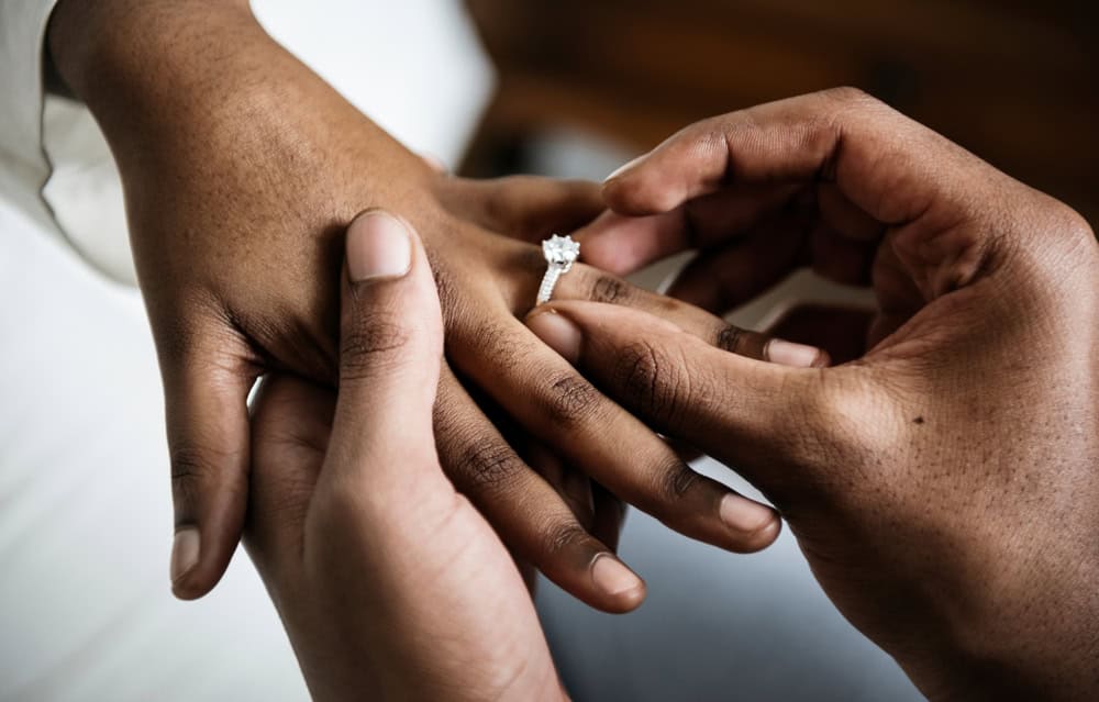 Man putting wedding ring on woman.