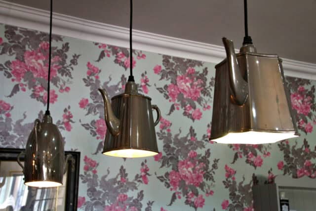 Silver tea kettle hanging lamps in a kitchen.