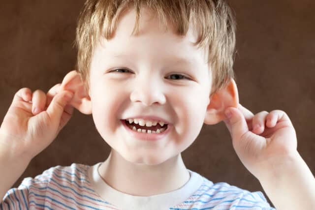 Little boy pulling his ears.