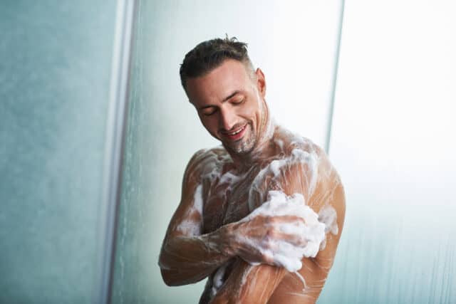 Man in the shower with soap.