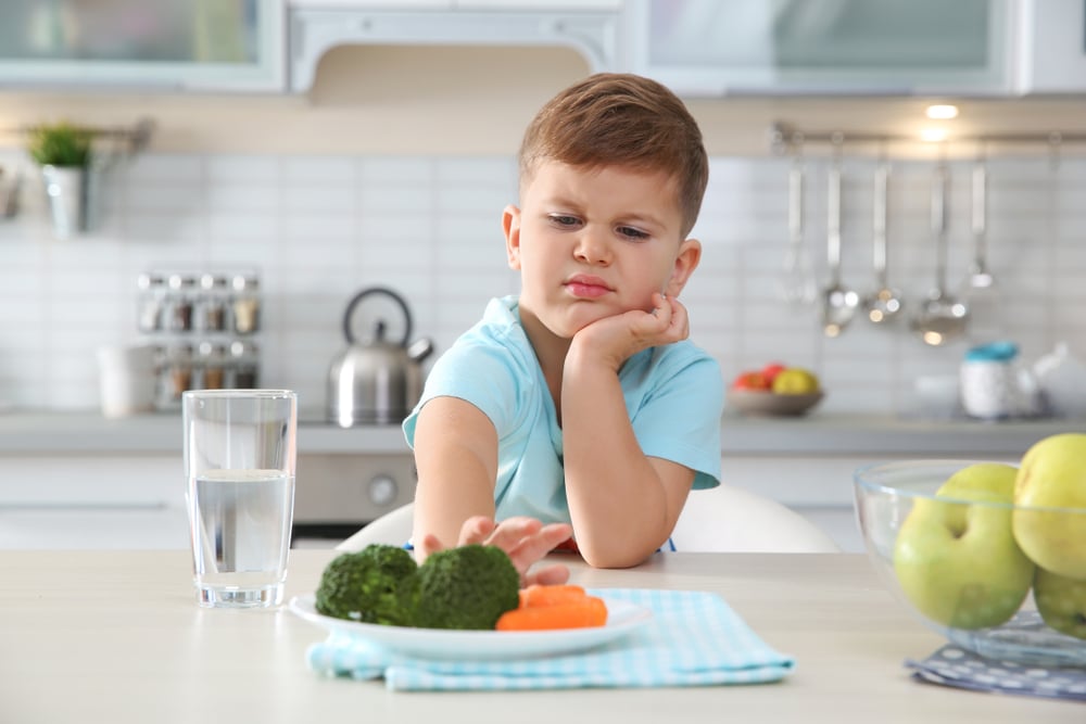 Boy refusing to eat his vegetables.