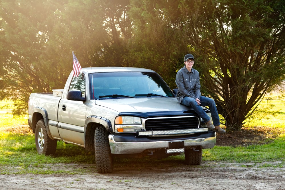Teenage boy in hood of his truck.