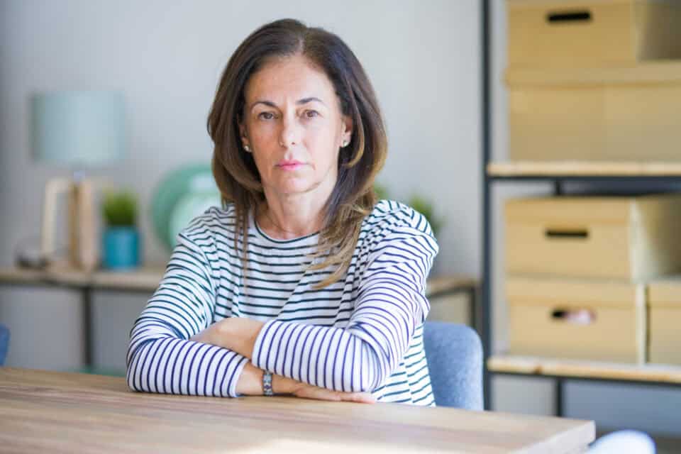 A beautiful middle age woman sitting with her hands folded on the desk