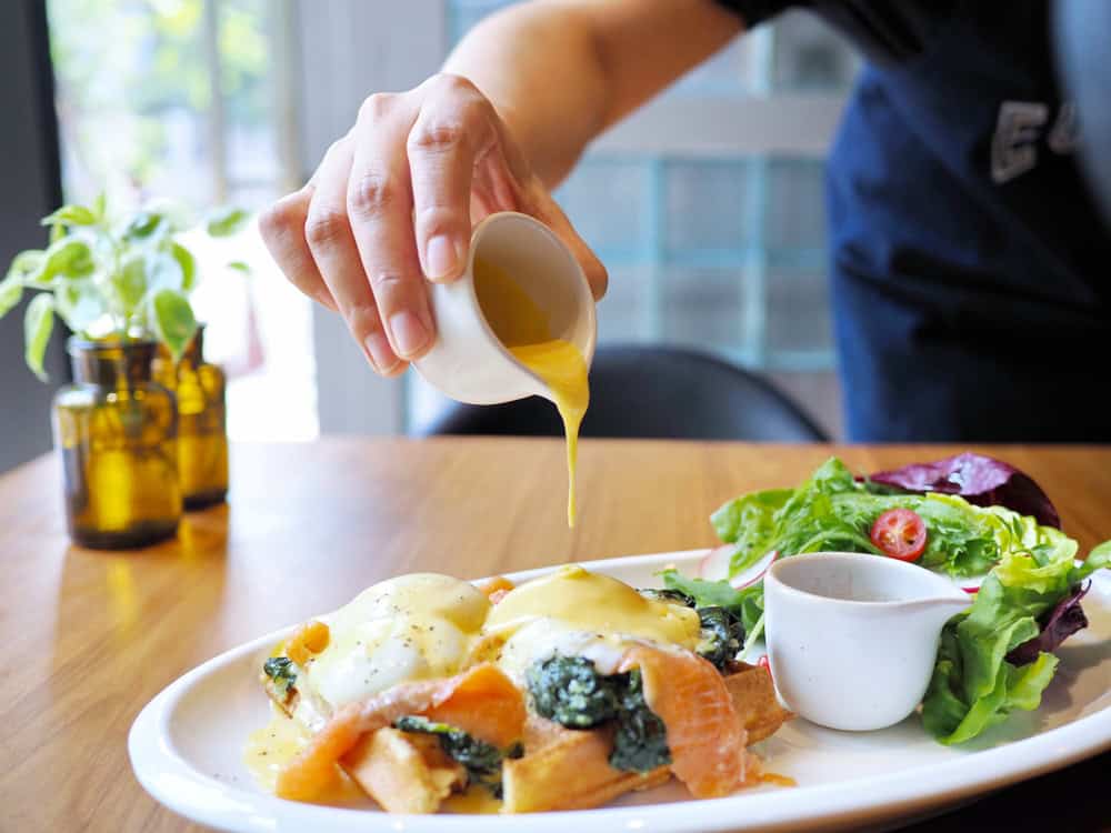 Woman pouring sauce over meal.