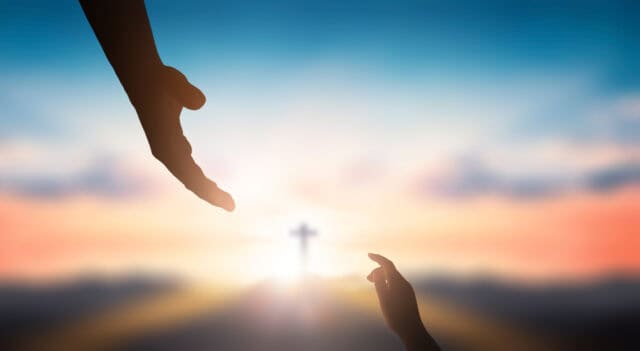 Two hands and a cross in the distance.