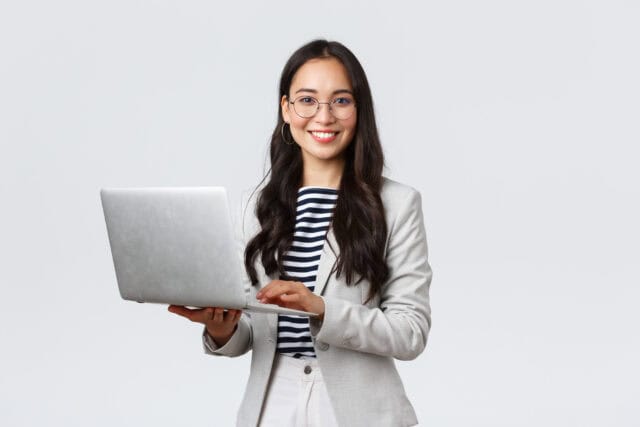 Woman holding a computer and looking confident.