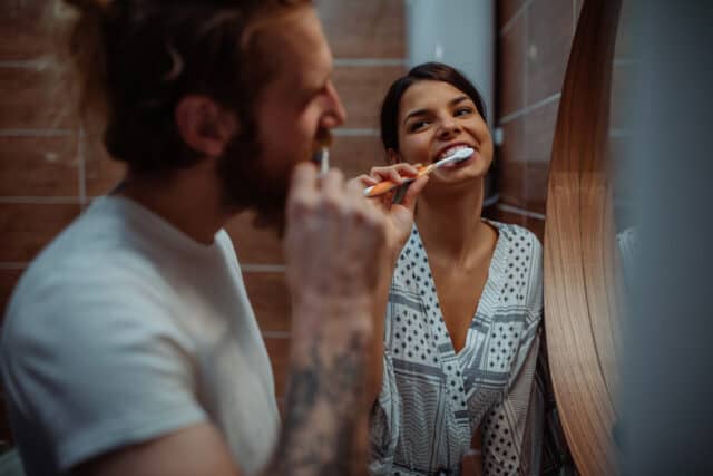 Couple brushing teeth together.