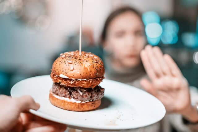A woman refuses a hamburger.