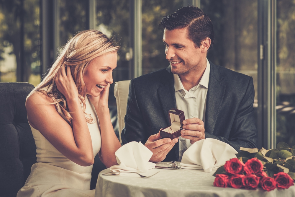 Man proposing to his girlfriend at a restaurant.