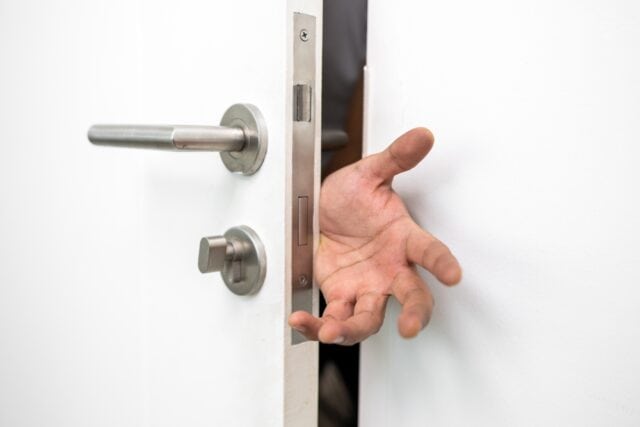 Hand in a door with a lock.