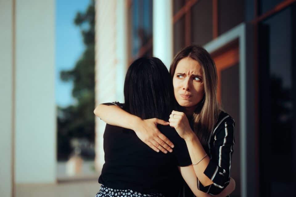 Envious woman hugging her friend.