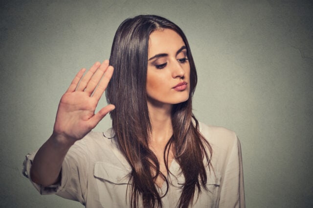 Woman with her hand up and eyes closed.