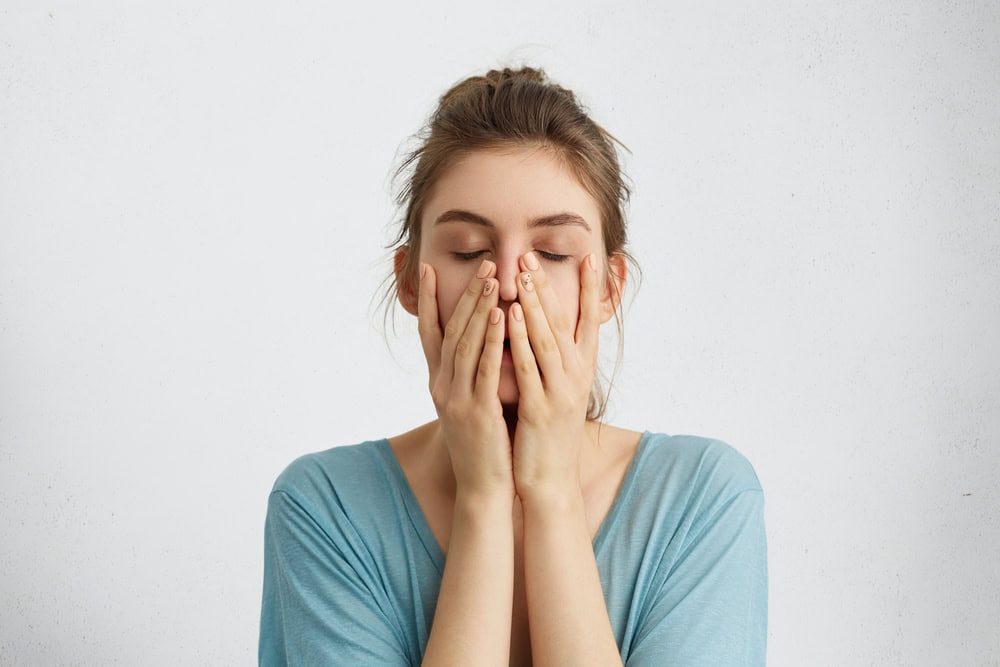 Woman upset with her hands over her face.
