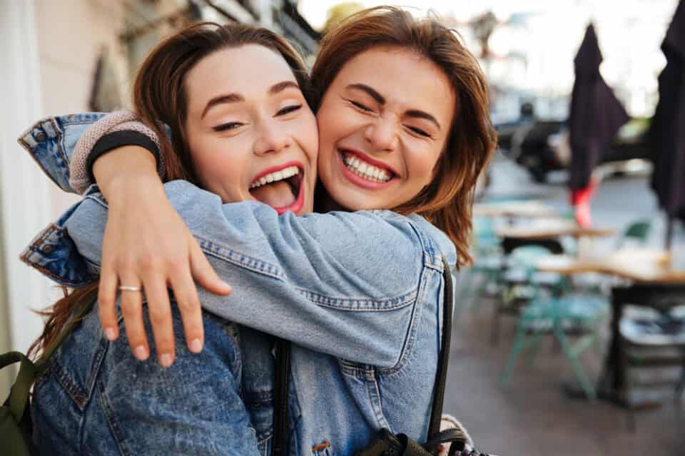 Laughing girlfriends hugging.