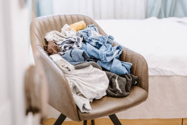 Pile of unfolded dirty clothes on a chair.