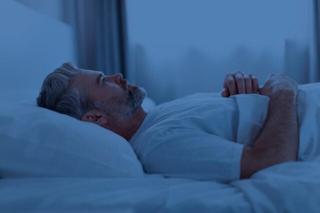 Insomnia, middle aged man trying to sleep.
