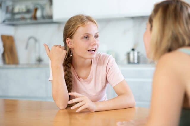 Young teen speaking with her mother.