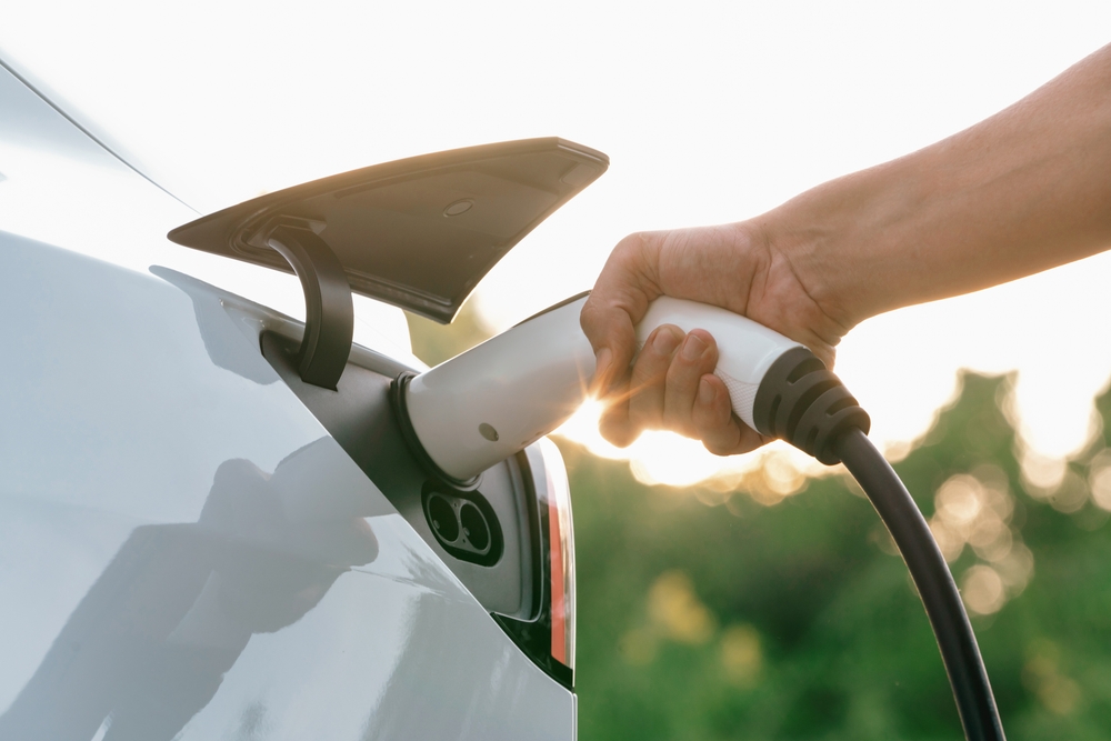 Man recharging battery of electric car.