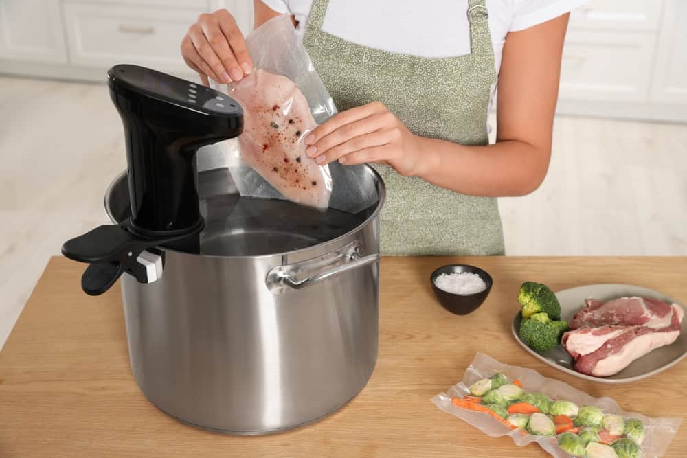 Woman with a pot of water in kitchen. 