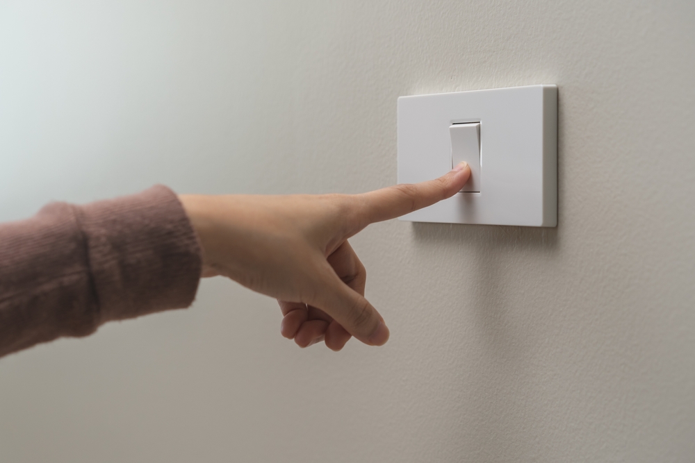 Hand turning off the lightswitch.