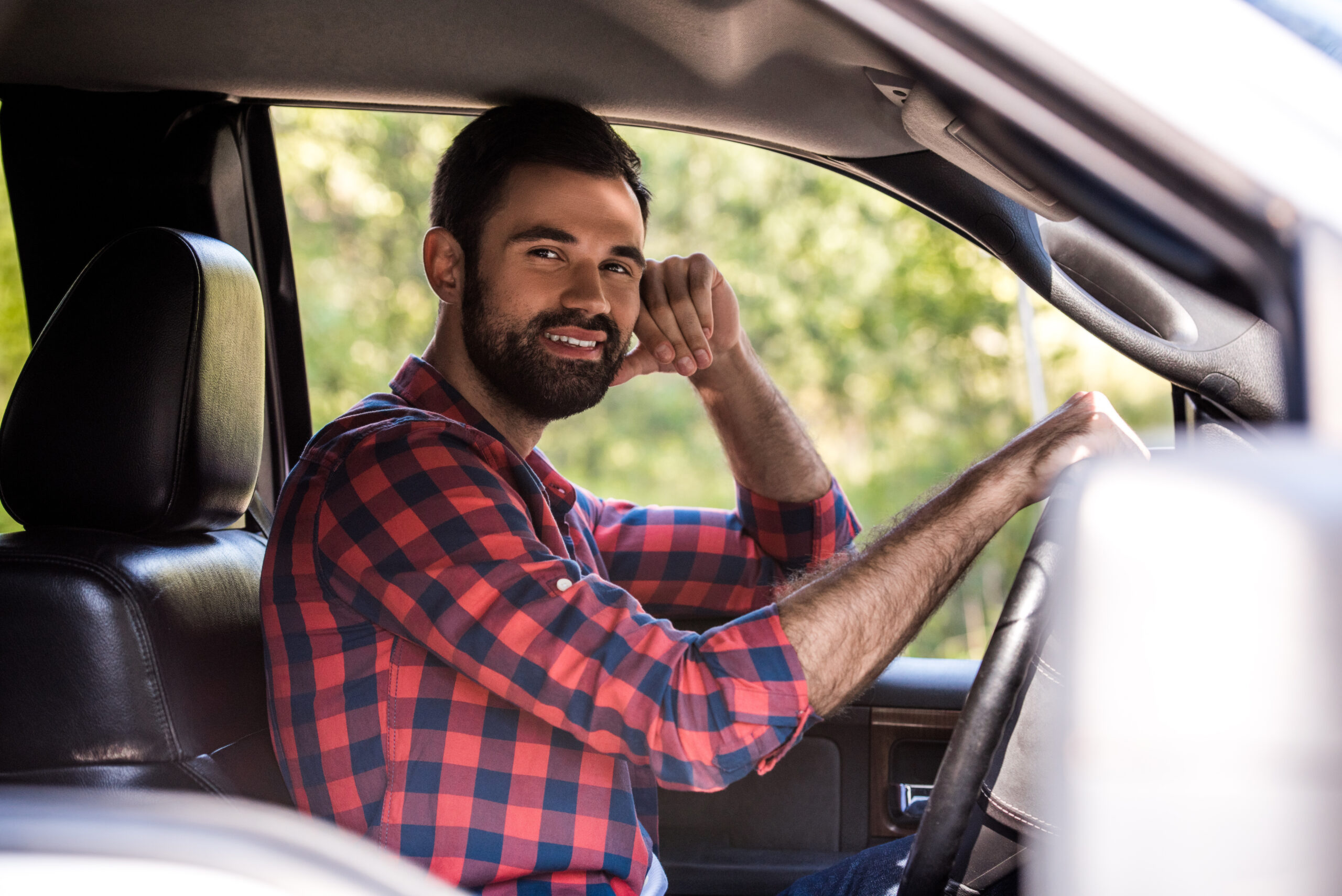 Man in front seat of car smiling.