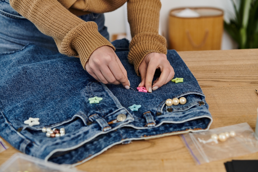 Young woman sewing jeans.