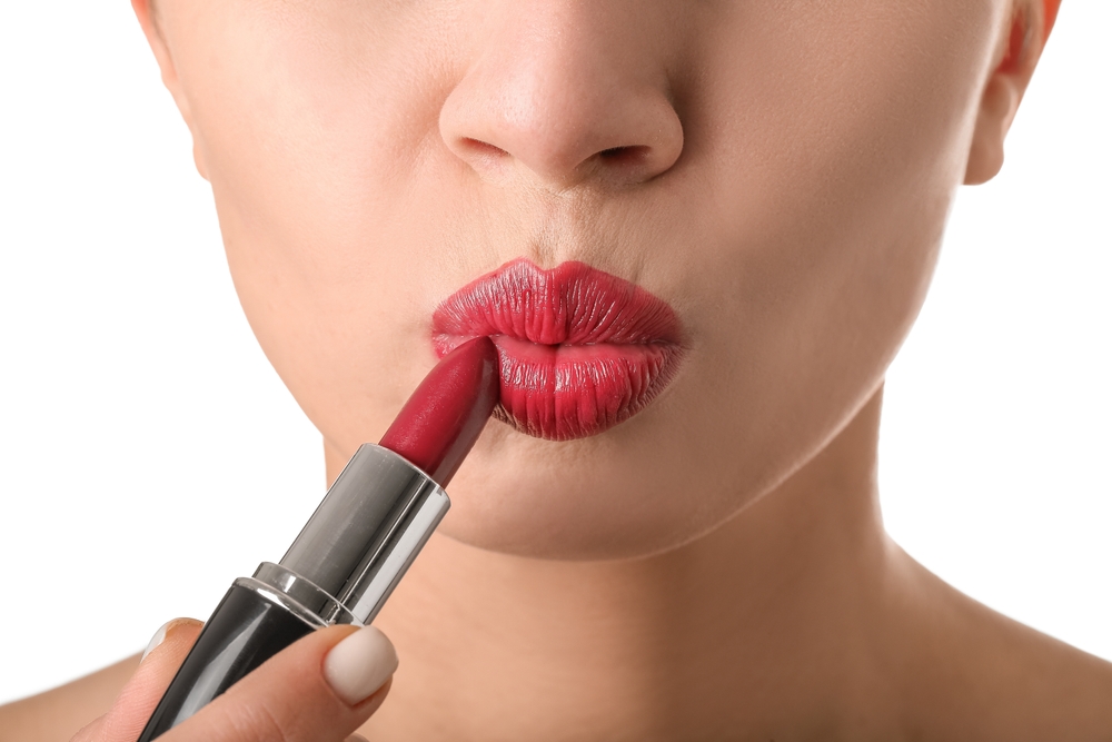 Woman applying red lipstick.