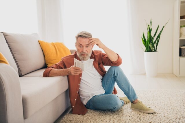 Senior man reading a text on his phone looking confused.