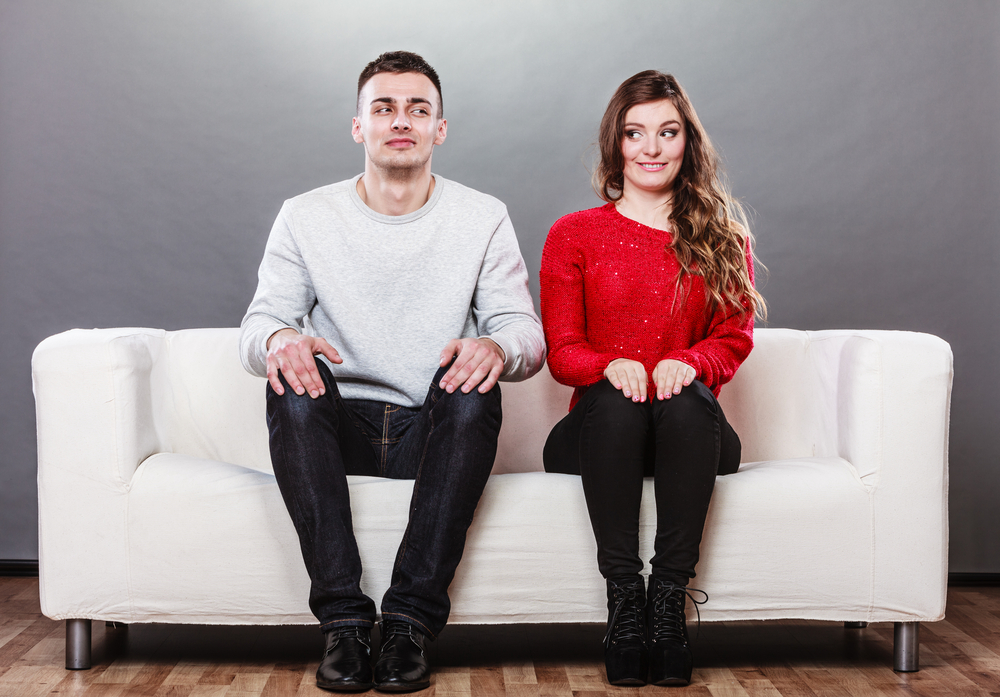 Man and woman sitting near one another not speaking.