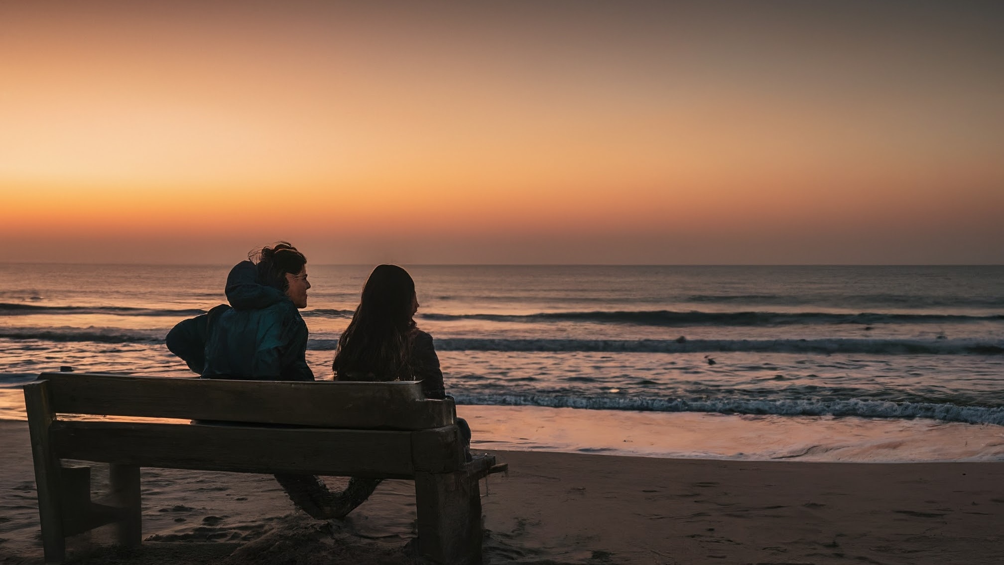 Man and woman sitting on the beach at night. 