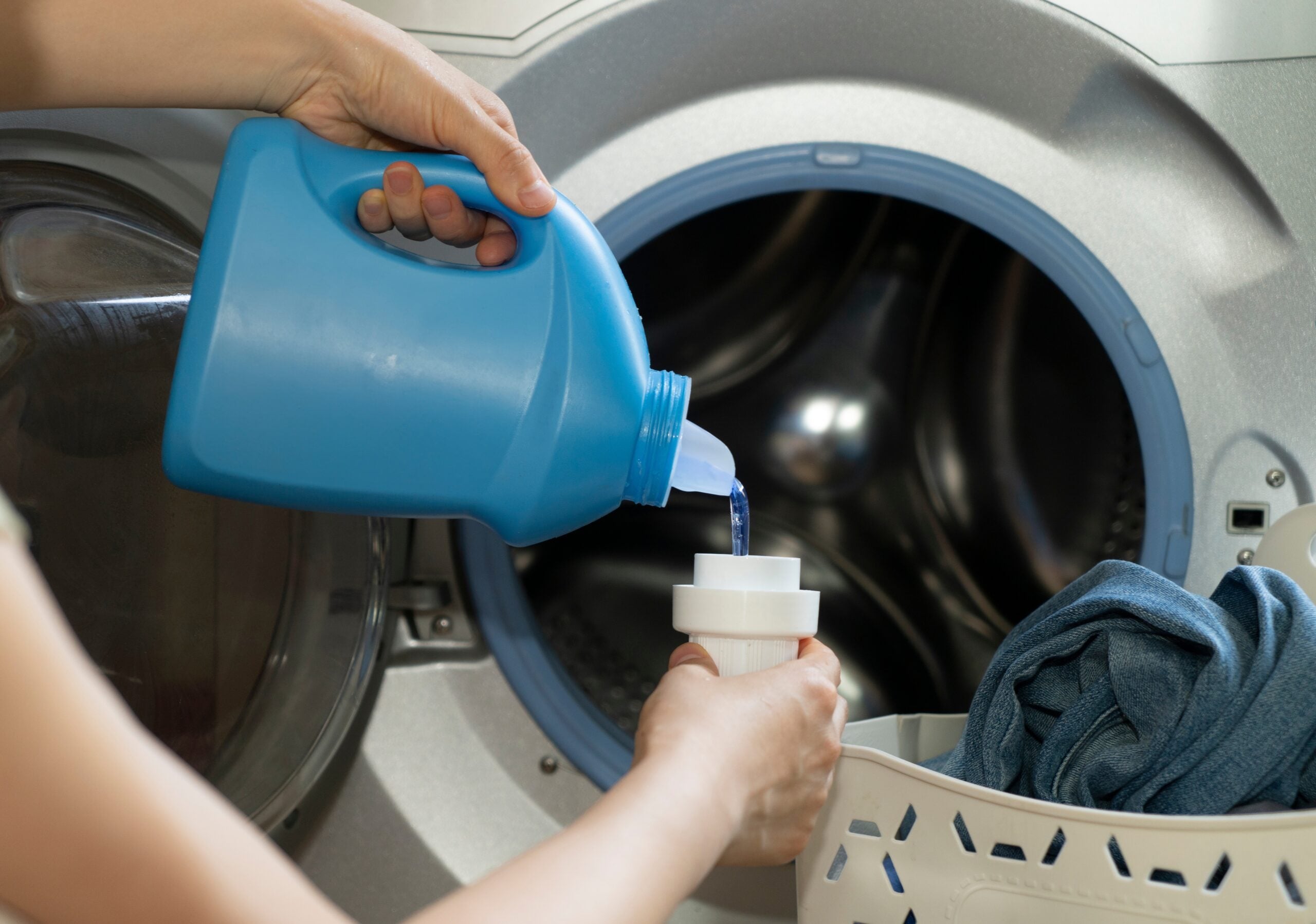 Adding laundry detergent to the washer.
