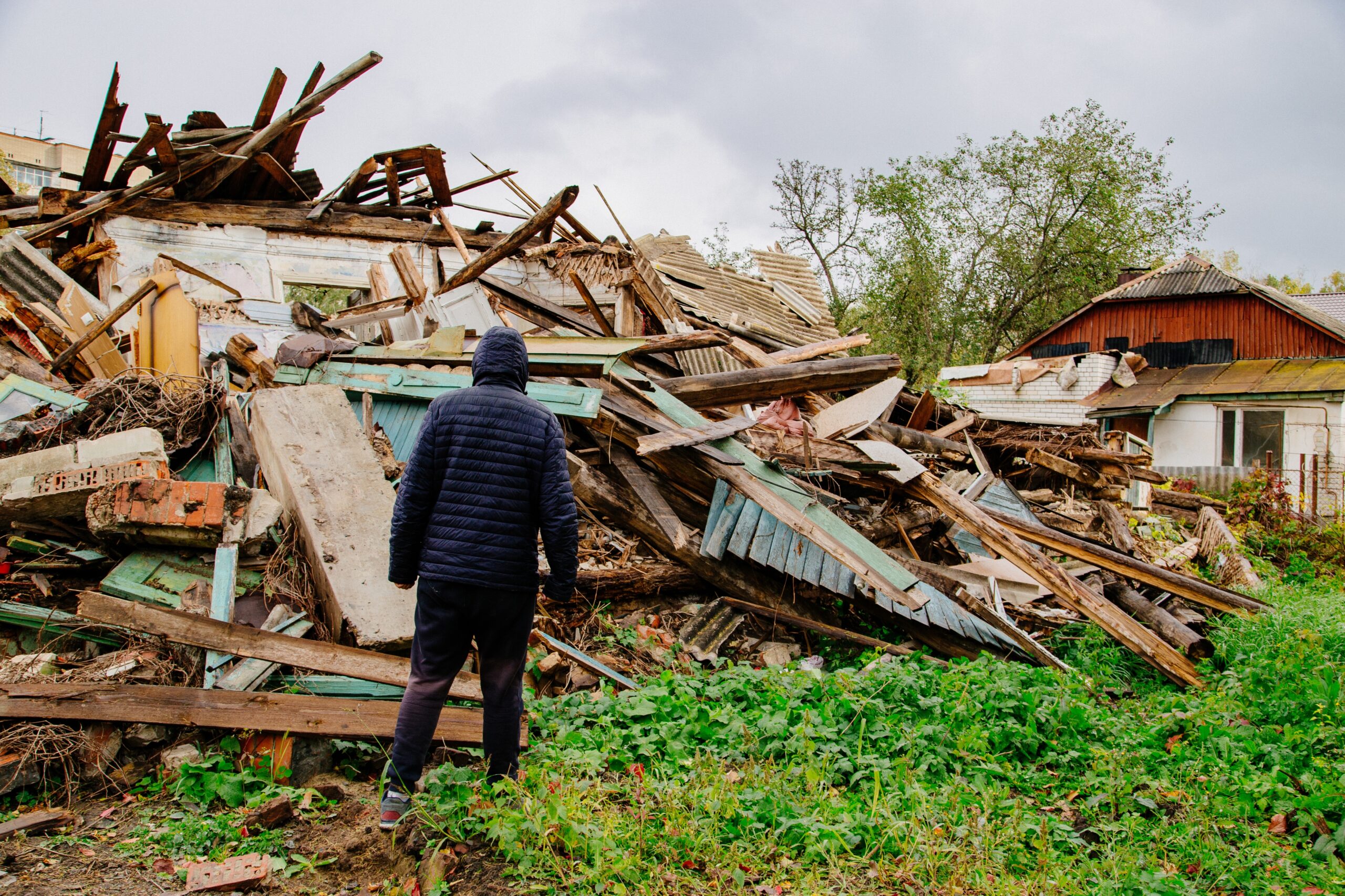 Man looking at his destroyed house after natural disaster.