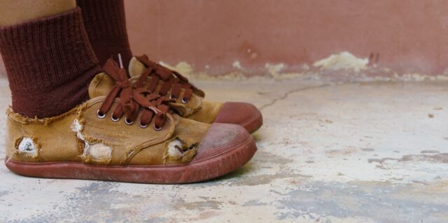 Torn worn out brown school shoes.