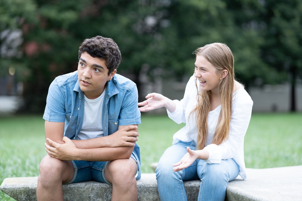 A young guy tired of listening to talkative girl at the park