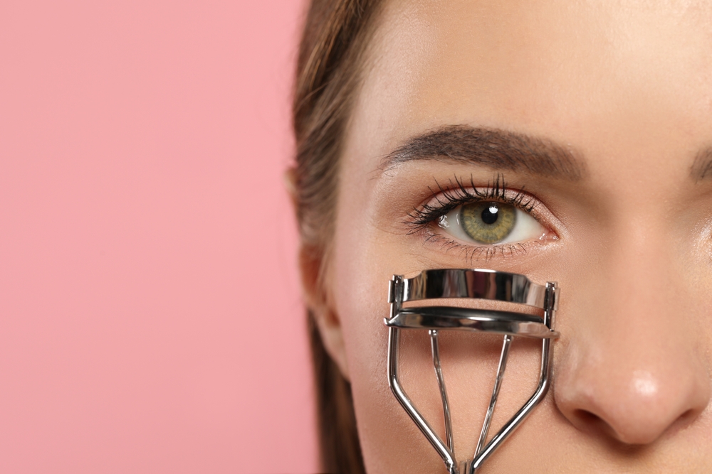 Woman using eye lash curler.