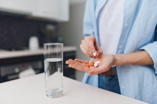 Woman holding supplements in hand.