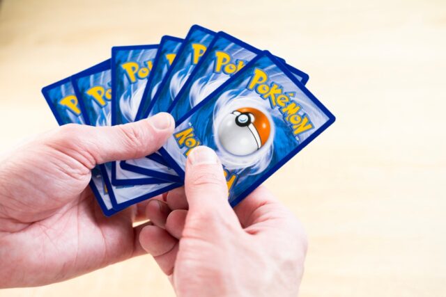 Hands holding Pokemon cards.