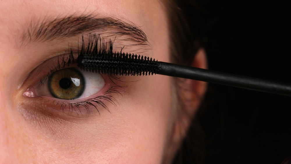 Woman applying mascara on her eyes.