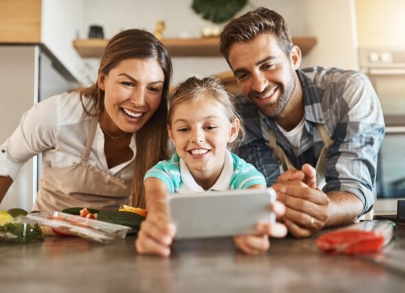 Mother and Father using smartphone with child to meal prep.