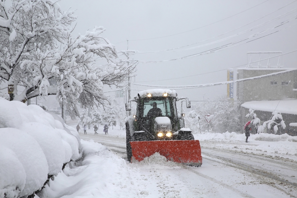 Tractor moving snow to clear street.