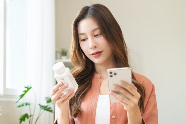 woman reading the back of supplement bottle