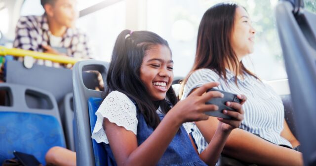 Happy girl, child and watching with phone on bus for entertainment or online streaming on Bus.