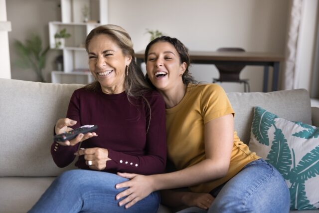 Mother and daughter laughing, watching a family movie together.