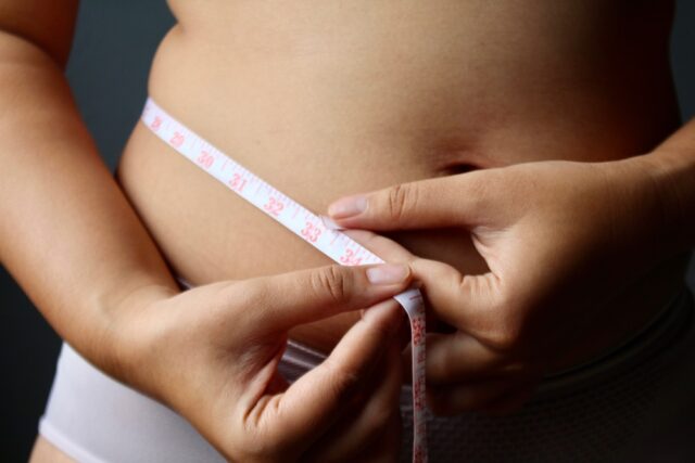 woman measuring her waist with measuring tape